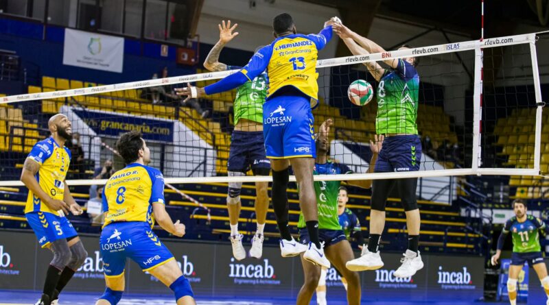 Un equip de jugadors de volèibol jugant un partit, un jugador està fent un remat i l'altre no l'ha pogut aturar