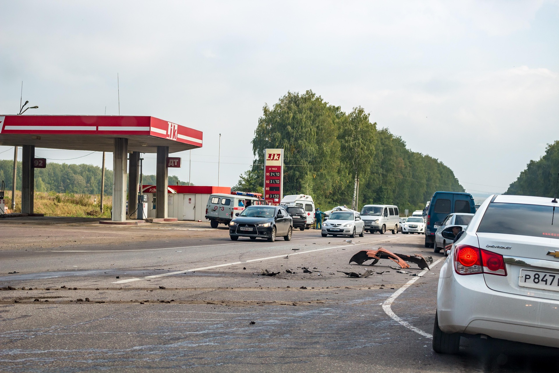 Restes d’un accident de trànsit a la carretera, amb vehicles aturats davant d’una benzinera.